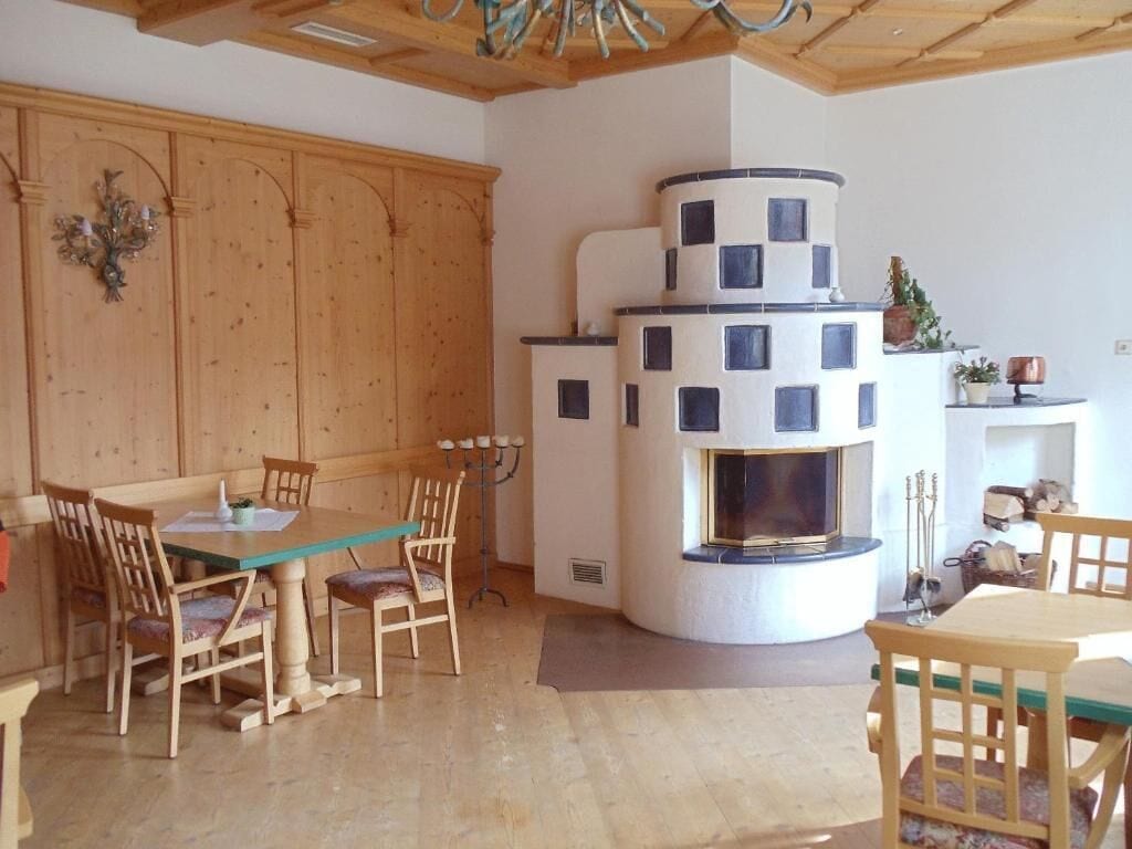 Ein gemütliches Wohnzimmer mit Holzbalkendecke, Kamin und Essbereich mit Holzmöbeln.