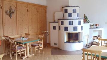 Ein gemütliches Wohnzimmer mit Holzbalkendecke, Kamin und Essbereich mit Holzmöbeln.
