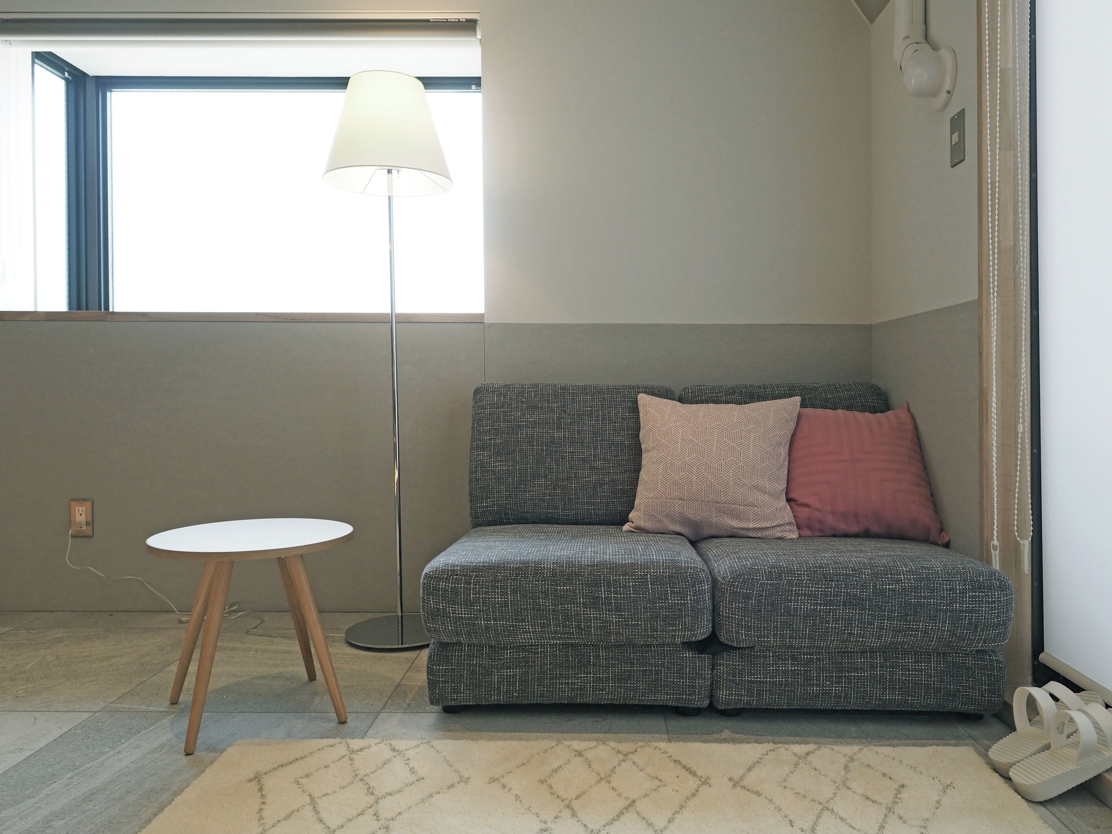 A modern living room with a grey patterned sofa, a white side table, and a floor lamp.