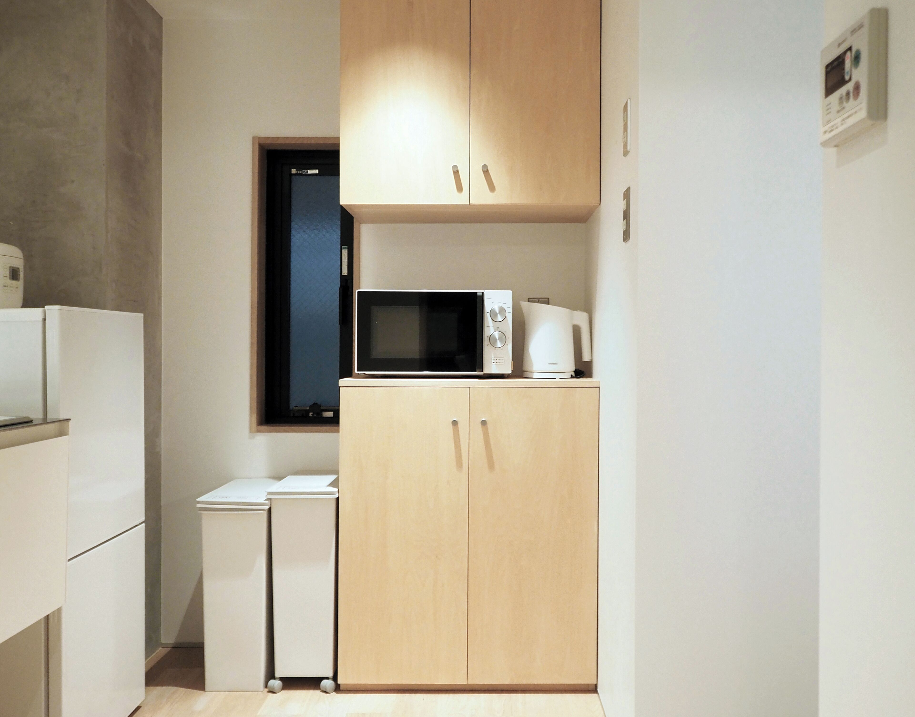 A compact kitchen with a microwave, a small refrigerator, and a coffee maker on a counter.