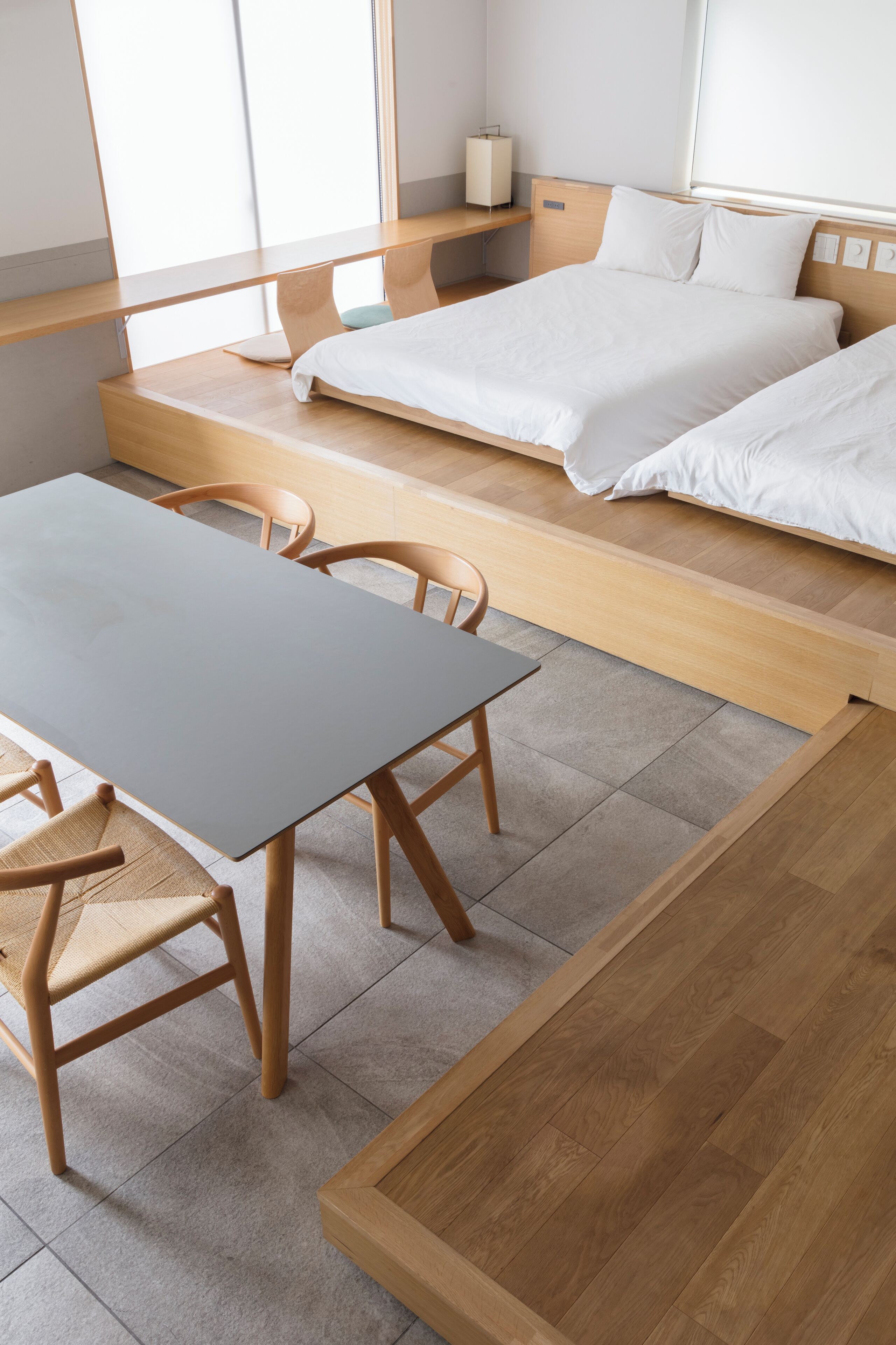 Una camera d'albergo moderna con un letto di legno, una scrivania e delle sedie.