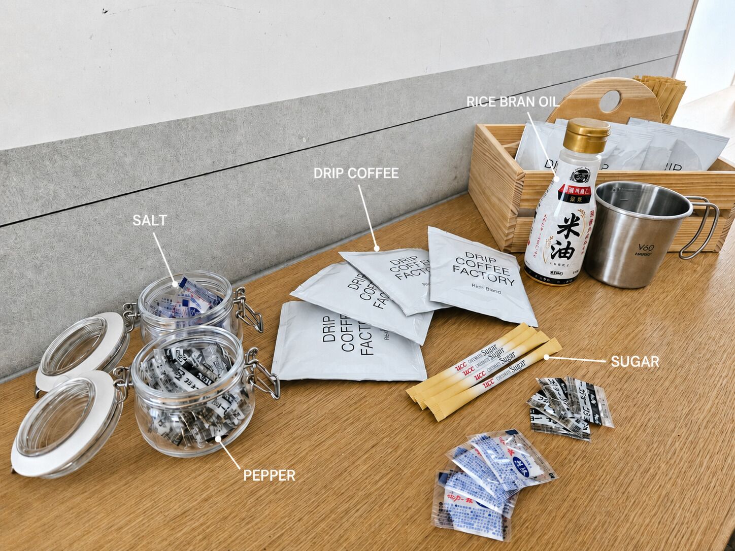A table with various coffee-related items including jars of salt, pepper, sugar, and packets of drip coffee.