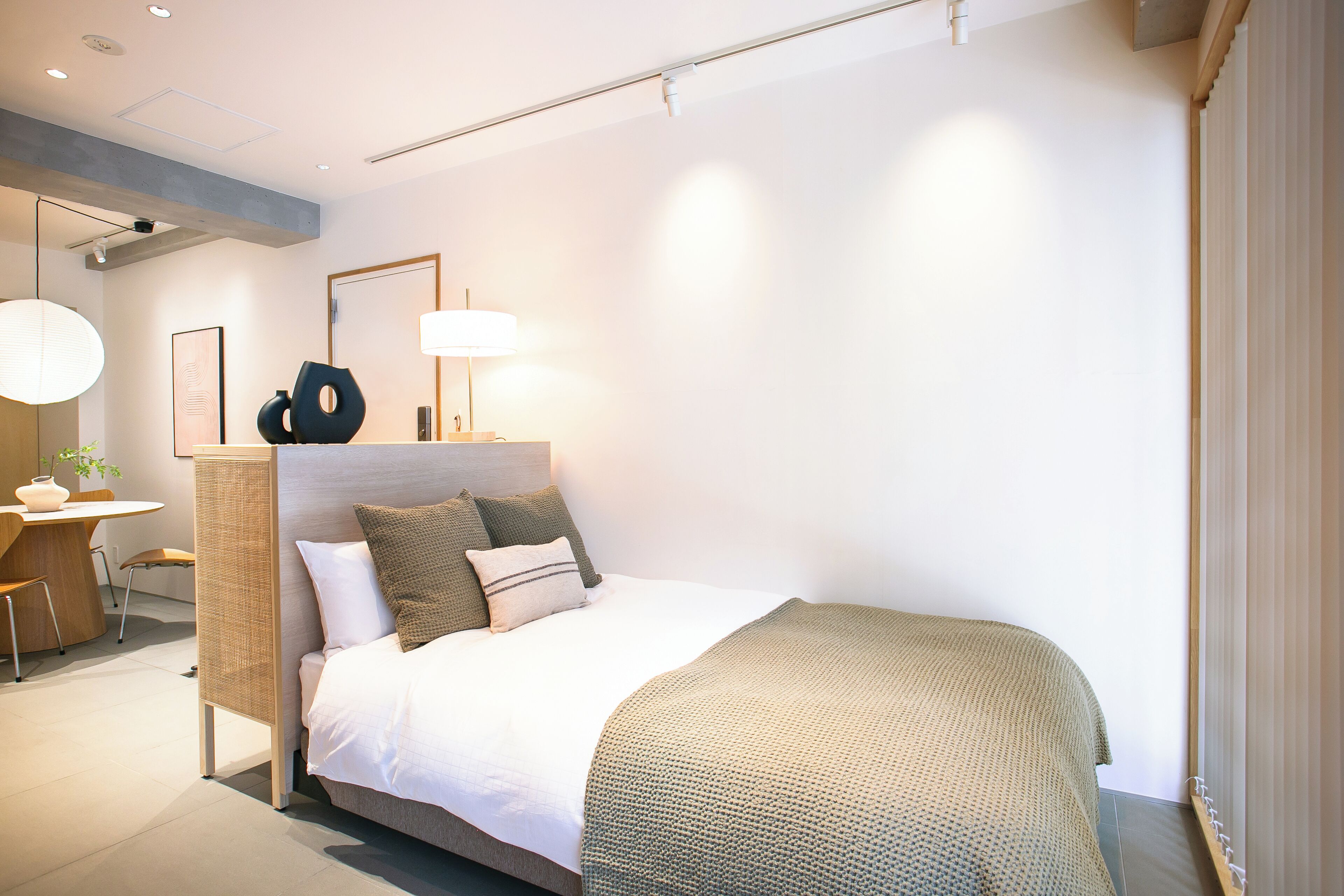 Une chambre d’hôtel moderne avec un lit bien fait, un bureau avec une chaise et une grande fenêtre équipée de stores.
