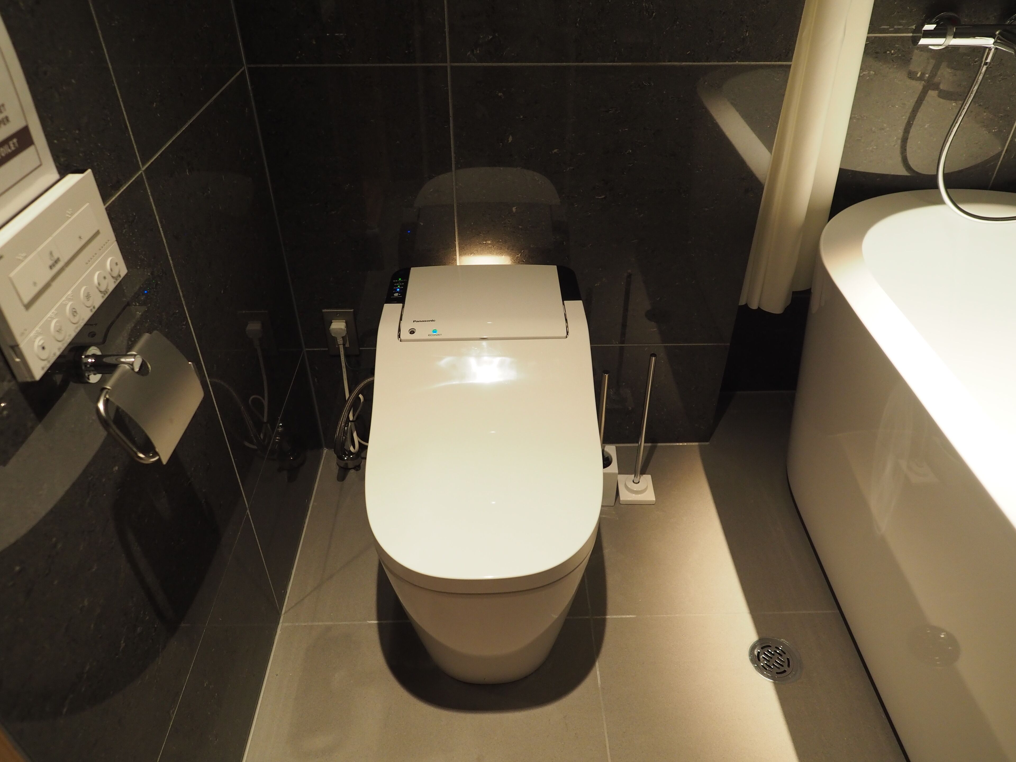 A modern bathroom with a white toilet, a bathtub, and a shower.