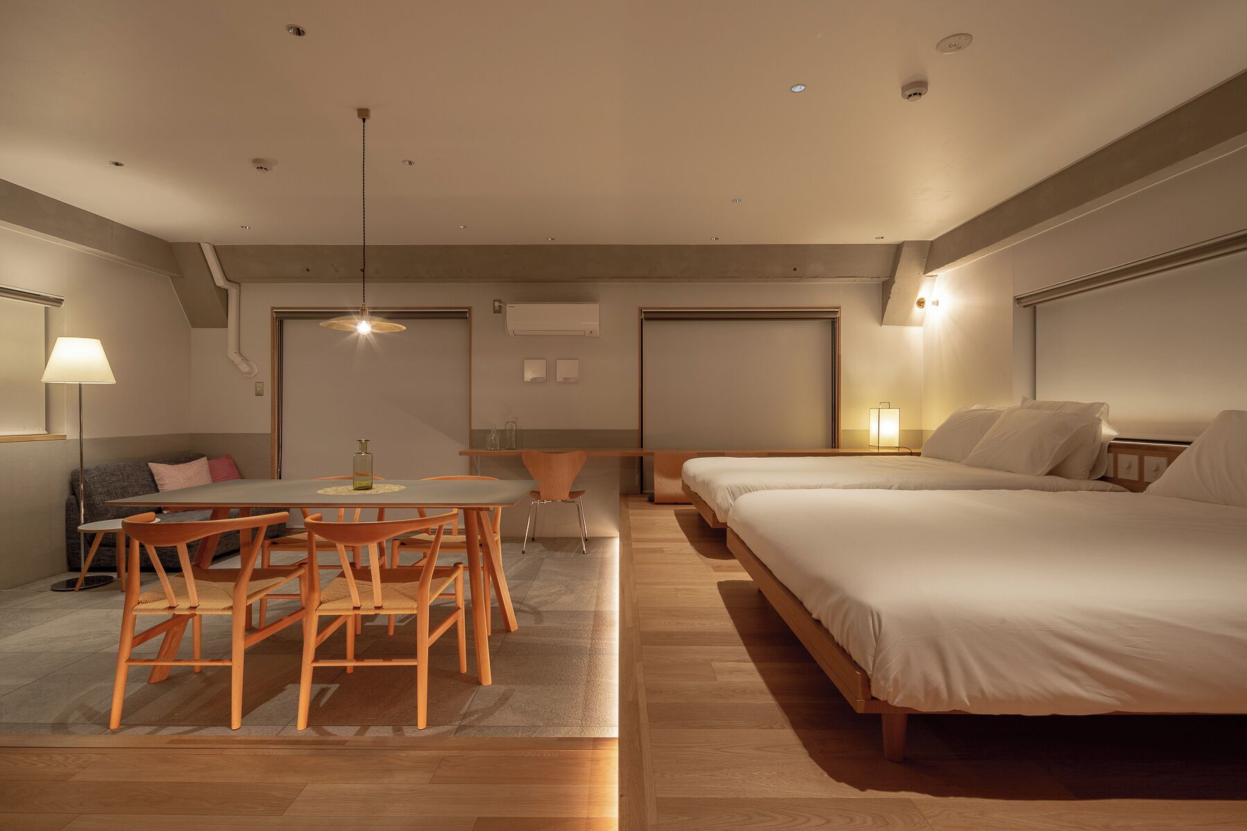 Une chambre d’hôtel moderne avec un grand lit, une table à manger avec des chaises, un canapé et un petit coin cuisine.
