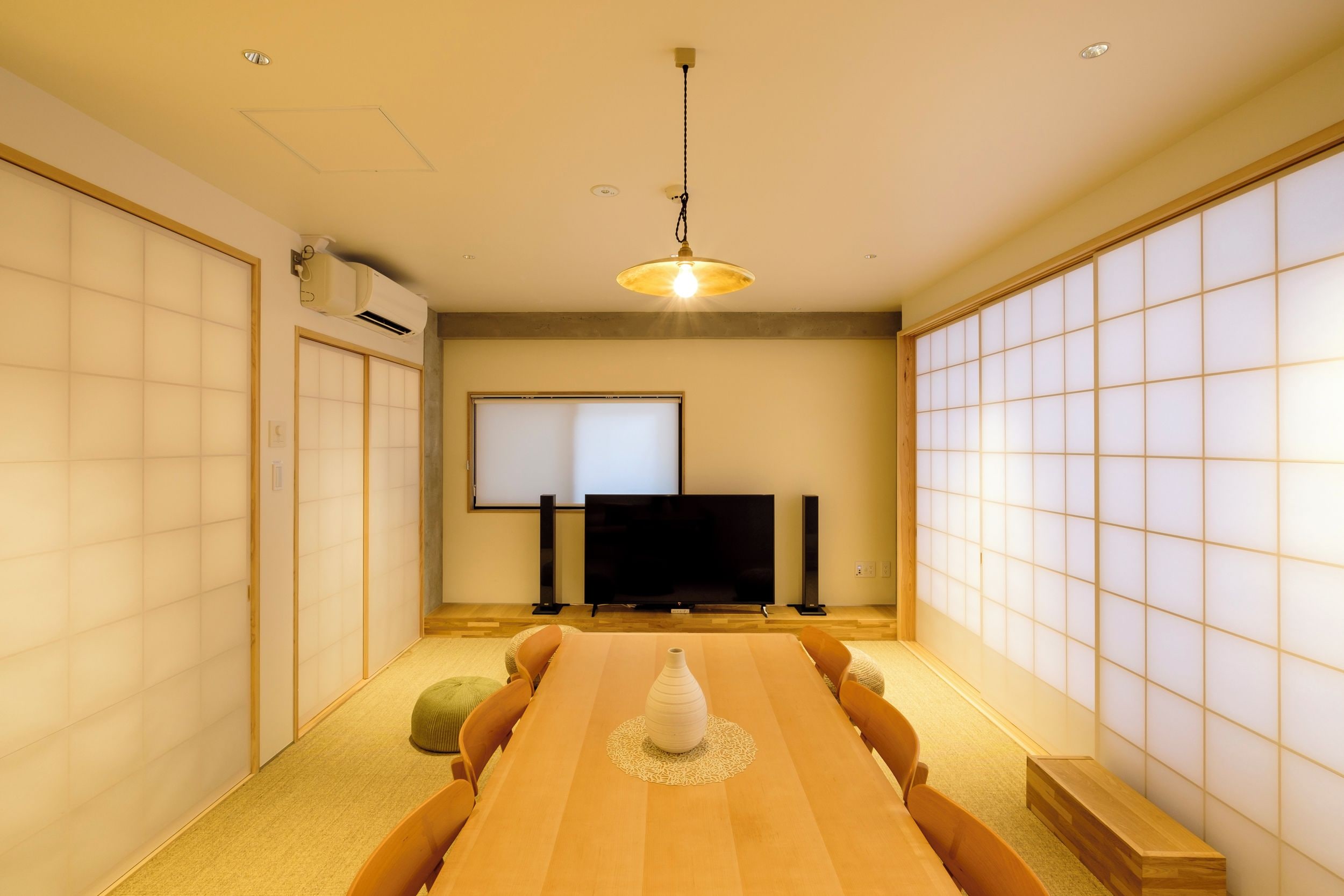 A conference room with a long table, chairs, a projector screen, and a television.