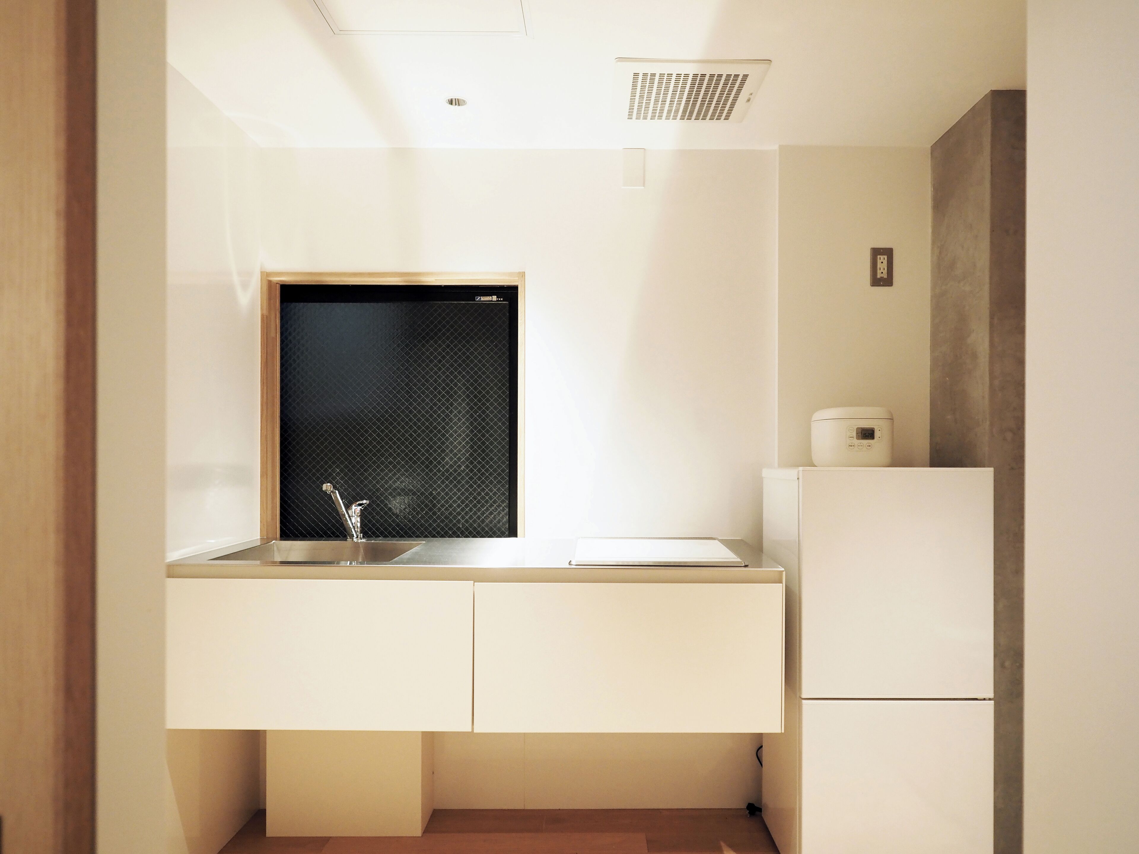 Eine moderne Küche mit integriertem Fenster, einer Spüle und einem Kühlschrank.