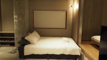 Un dormitorio moderno con cama, mesita de noche, armario de madera y televisor montado en la pared.
