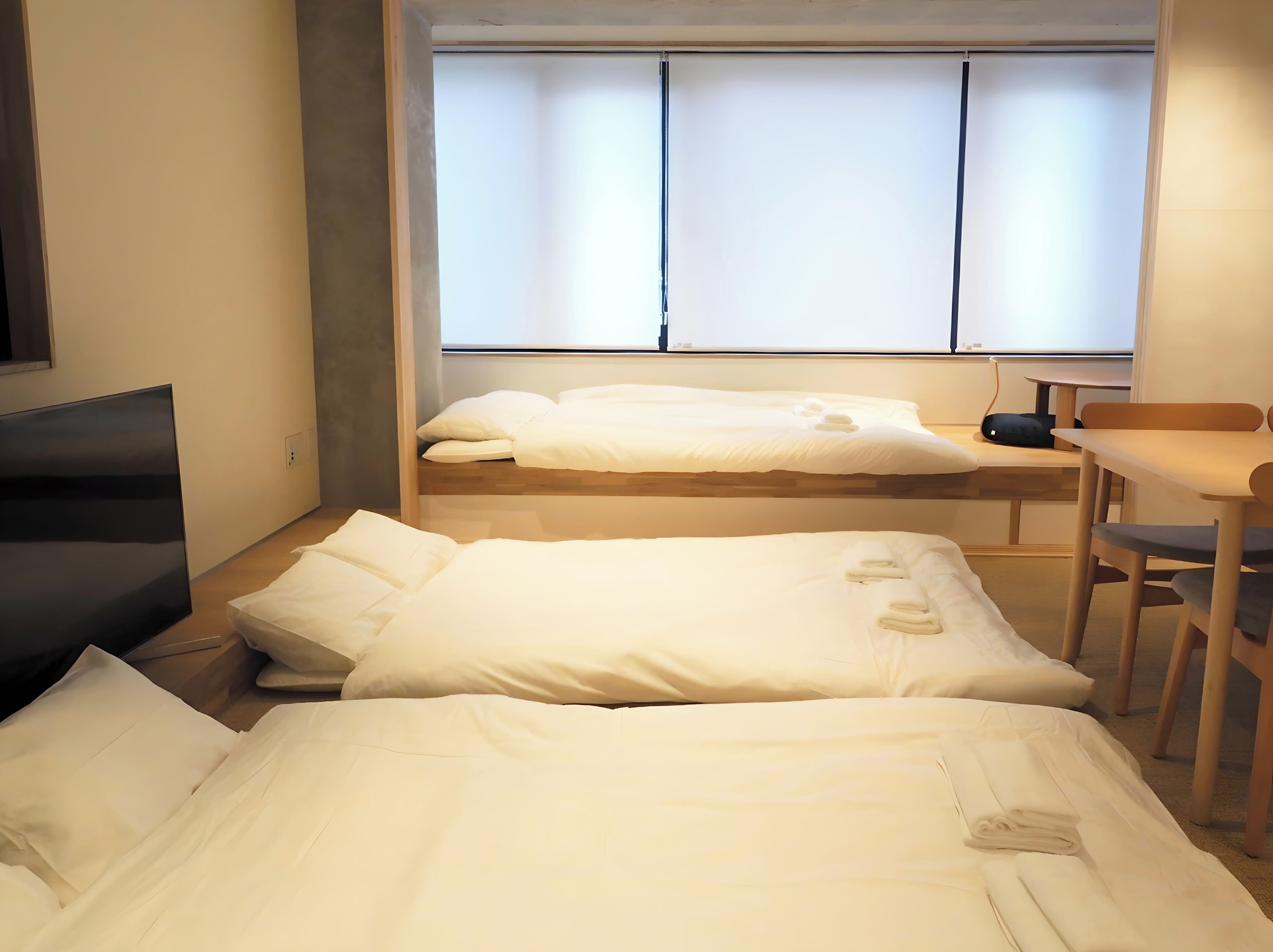 A hotel room with two beds, a desk, and a chair.