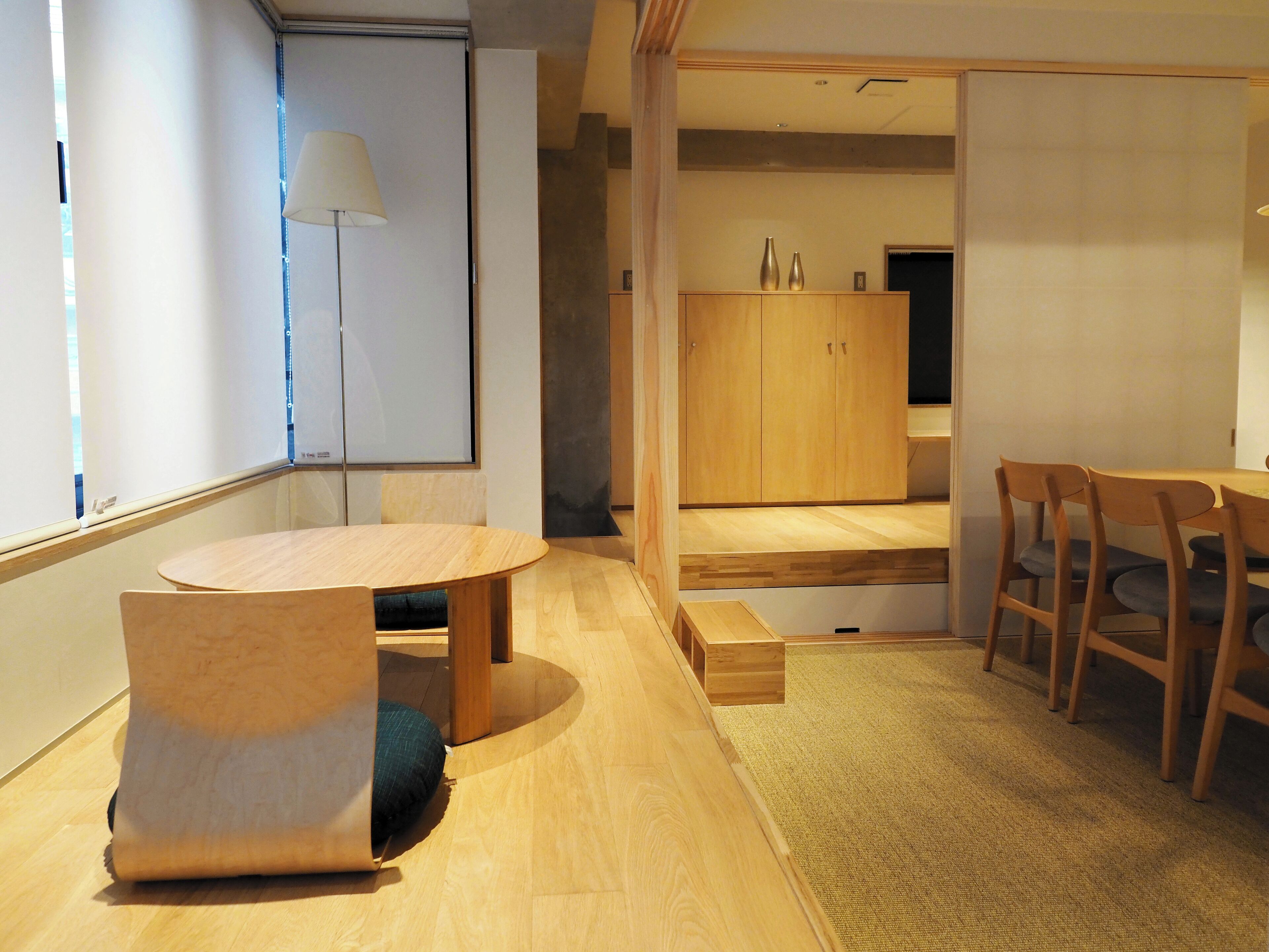 A modern, minimalist room with a wooden table and chairs, a sofa, and a cabinet.