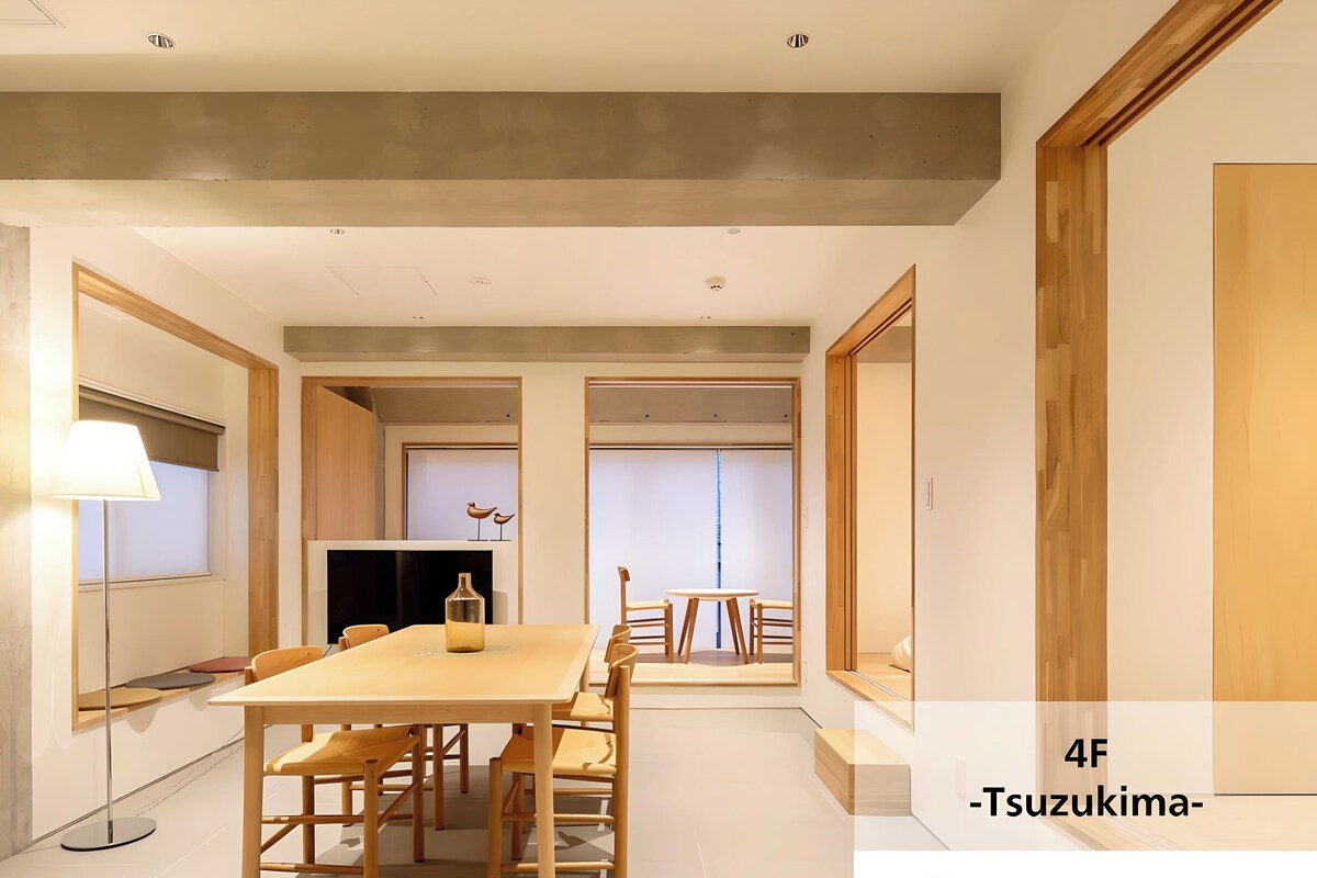 A modern dining area with a wooden table and chairs, a lamp, and a television.