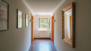 A hallway with framed pictures on the walls, a window with a view of trees, and a radiator on the floor. - Noon Mirch Hotel Restaurant (Eching)