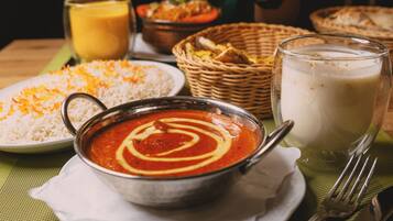Una mesa con un tazón de sopa, un plato de arroz, un vaso de leche y una cesta de pan.