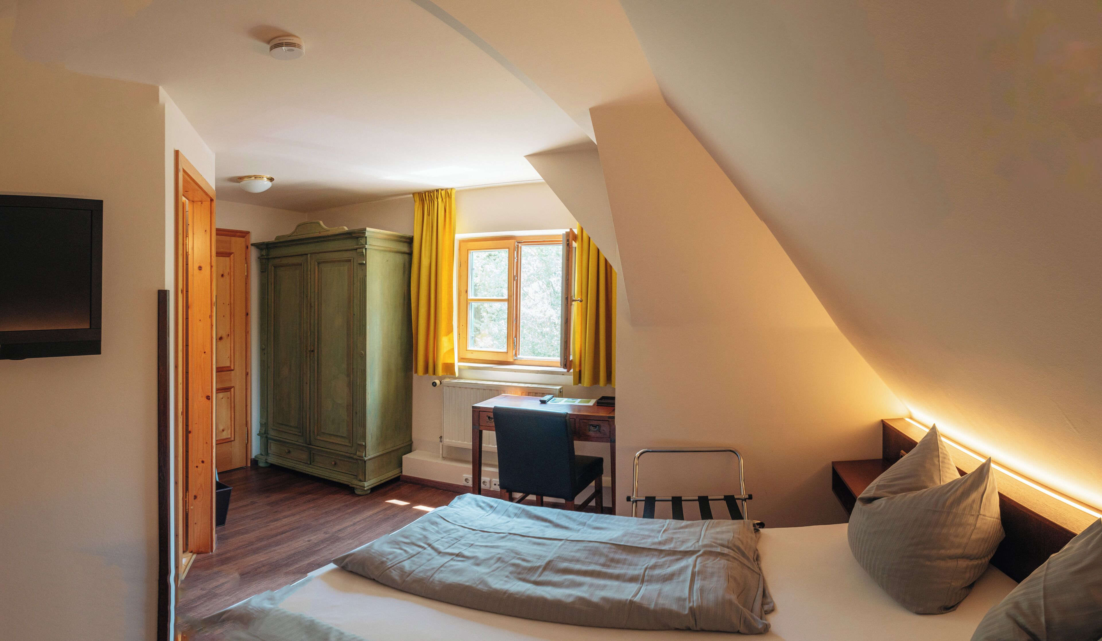 A bedroom with a bed, a desk, a chair, and a wardrobe.