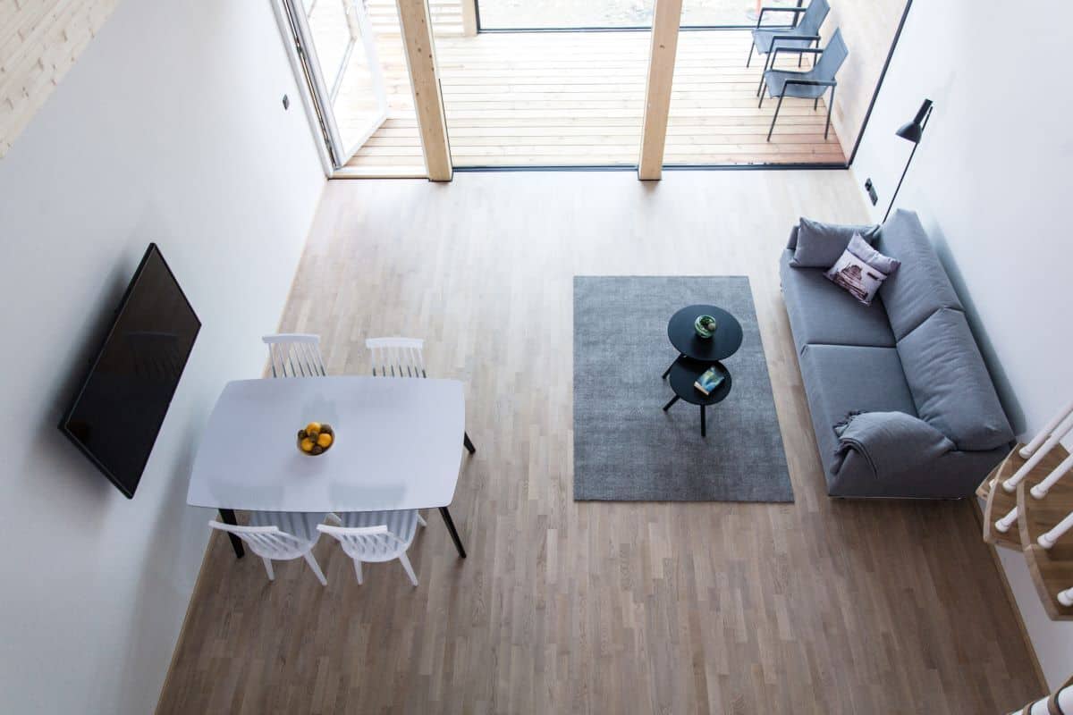 A modern living room with a dining area, a grey sofa, and a TV mounted on the wall.