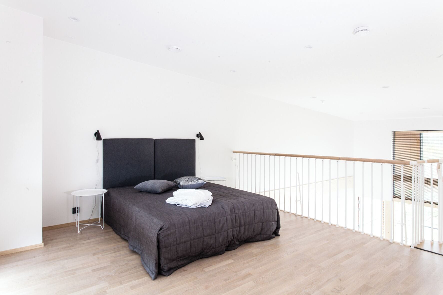 Un dormitorio moderno con una cama grande, una mesita de noche pequeña y vistas a un balcón.