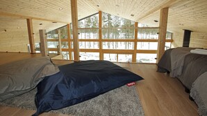 A cabin with a high ceiling, wooden beams, and large windows offering a view of a snowy forest. - Eerikkilä Sport & Outdoor Resort (Tammela)
