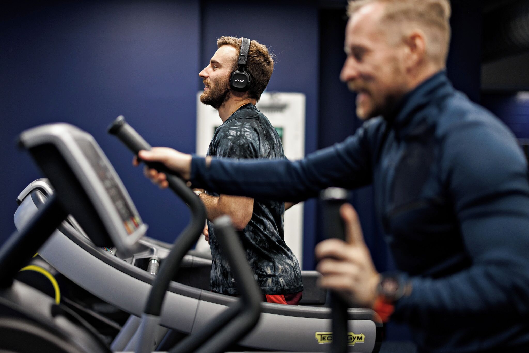 Une salle de sport avec des tapis de course, et une personne qui en utilise un.