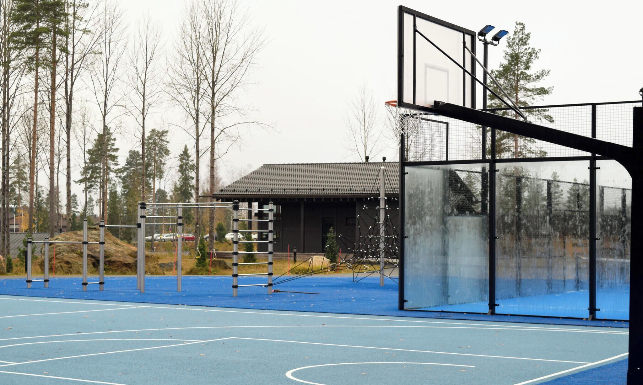A basketball court with a net, metal poles, and a building in the background.