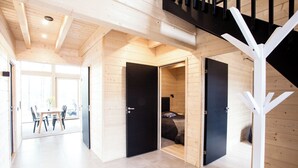 A modern interior with wooden walls, a staircase, and a dining area with chairs and a table. - Eerikkilä Sport & Outdoor Resort (Tammela)