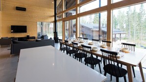 A modern dining area with large windows, a flat-screen TV, and a cozy seating area. - Eerikkilä Sport & Outdoor Resort (Tammela)