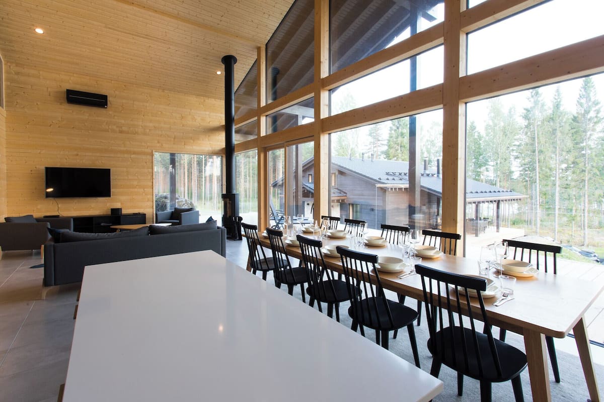 A modern dining area with large windows, a flat-screen TV, and a cozy seating area.