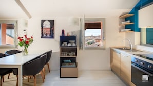 A modern kitchen with a view, a dining area with a vase of flowers, and a small shelf unit.