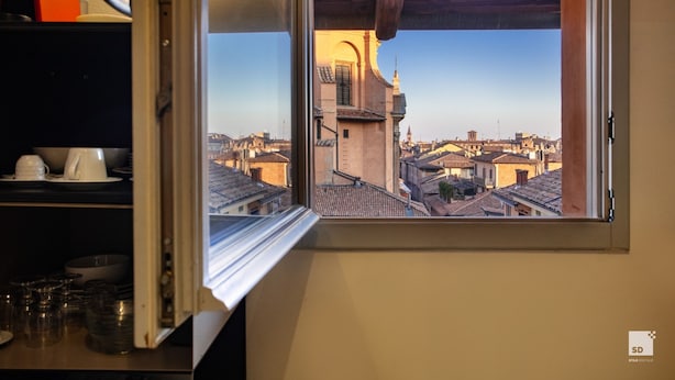 A view from a window overlooking a cityscape with traditional buildings and a prominent tower.