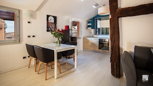 A modern kitchen with a built-in oven and a dining area with a white table and black chairs.