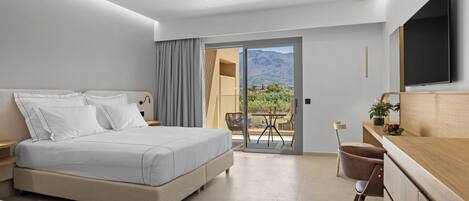 A modern hotel room with a large bed, a desk, a chair, a TV, and a balcony with a mountain view.