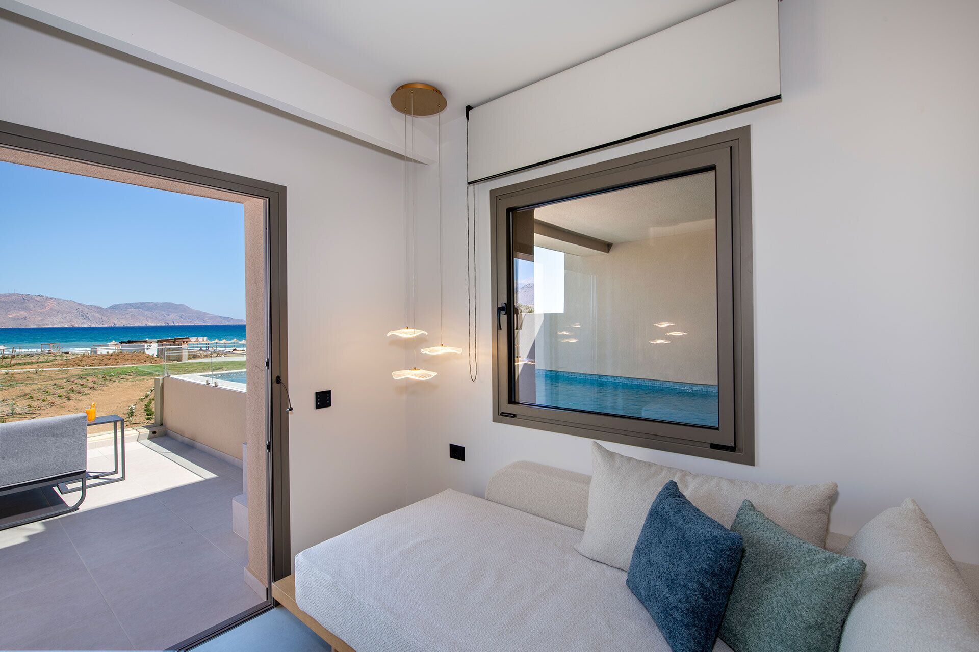 Un dormitorio con un ventanal grande, una cama y vista a la playa.