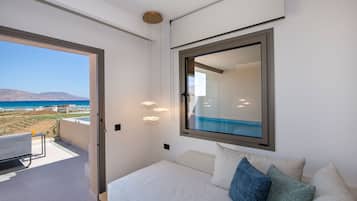 Un dormitorio con un ventanal grande, una cama y vista a la playa.