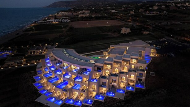 Un hotel moderno con varios balcones y piscinas, cerca de una playa.