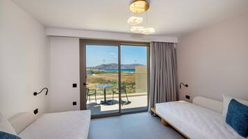 A hotel room with a balcony, a bed, a table, and a view of the beach.