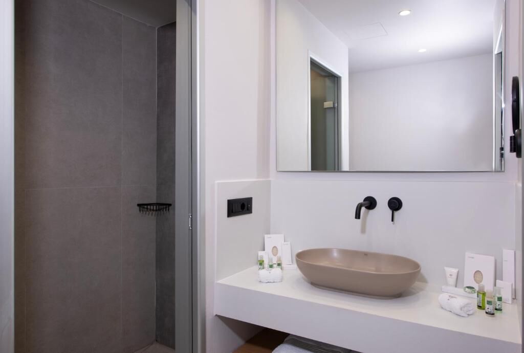 A modern bathroom with a beige sink, a large mirror, and a shower area.
