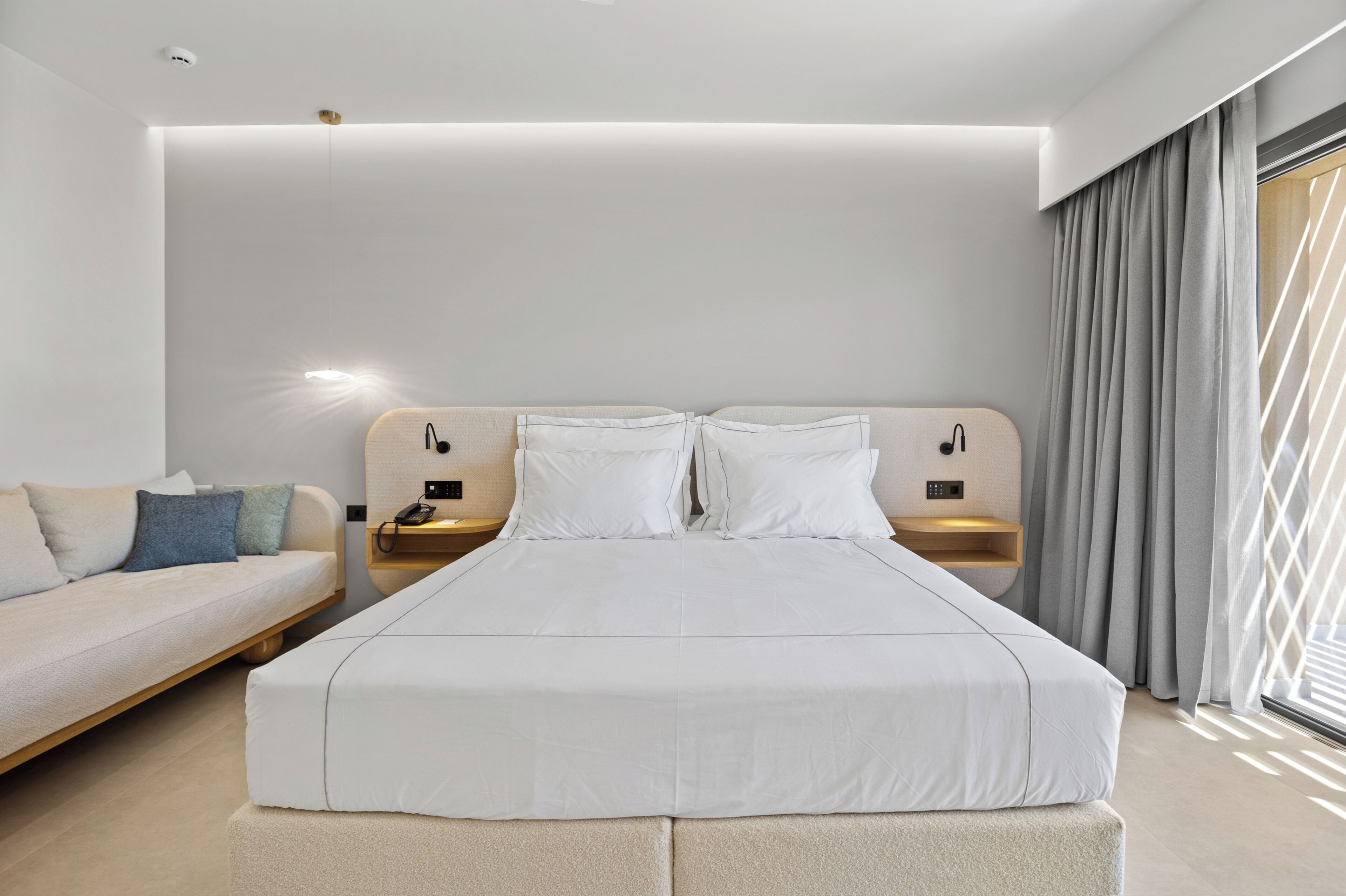 Una habitación de hotel moderna con una cama grande, un sofá, una mesita de noche y un pupitre.