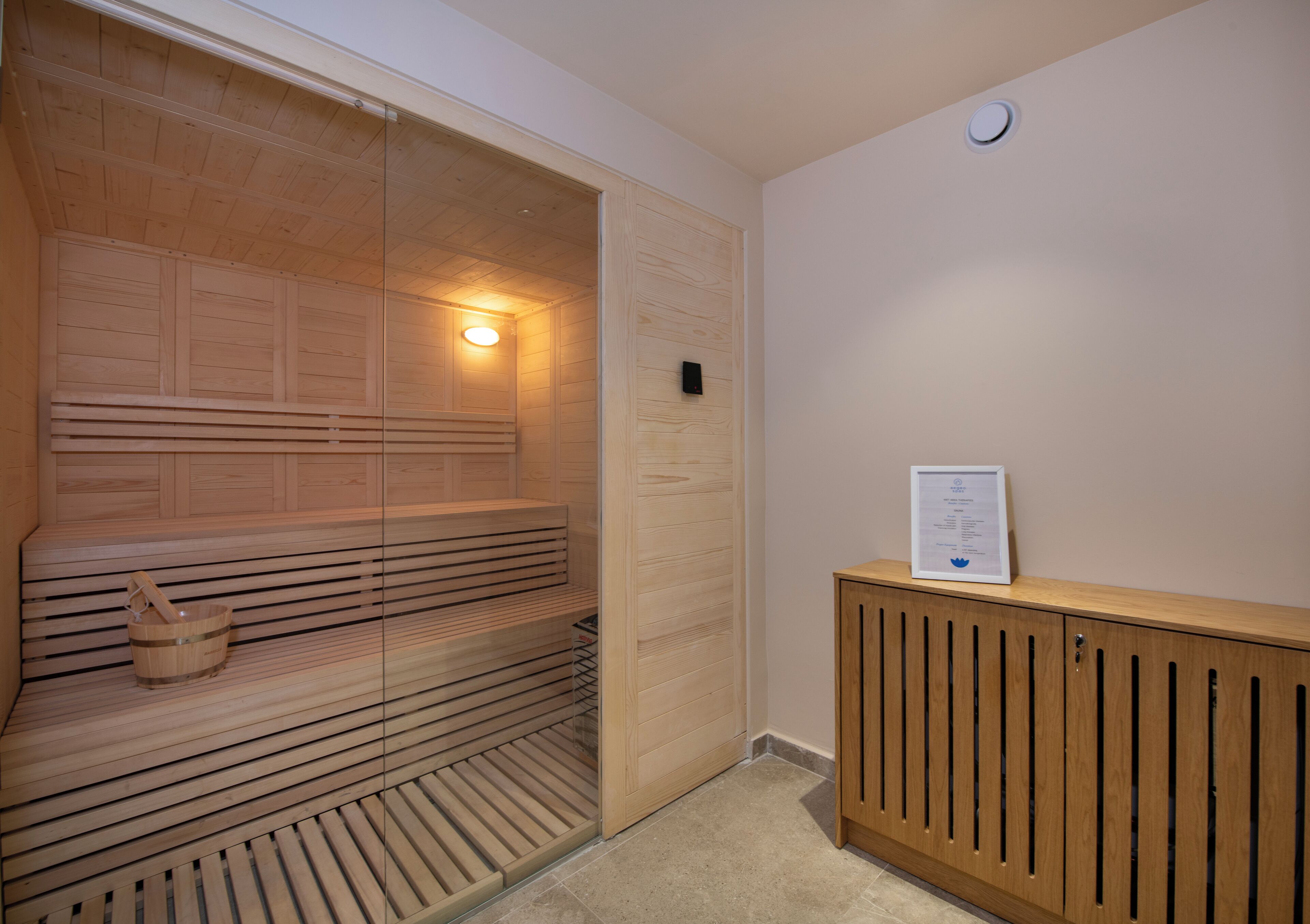 A sauna with wooden benches and a wooden cabinet with a certificate on top.