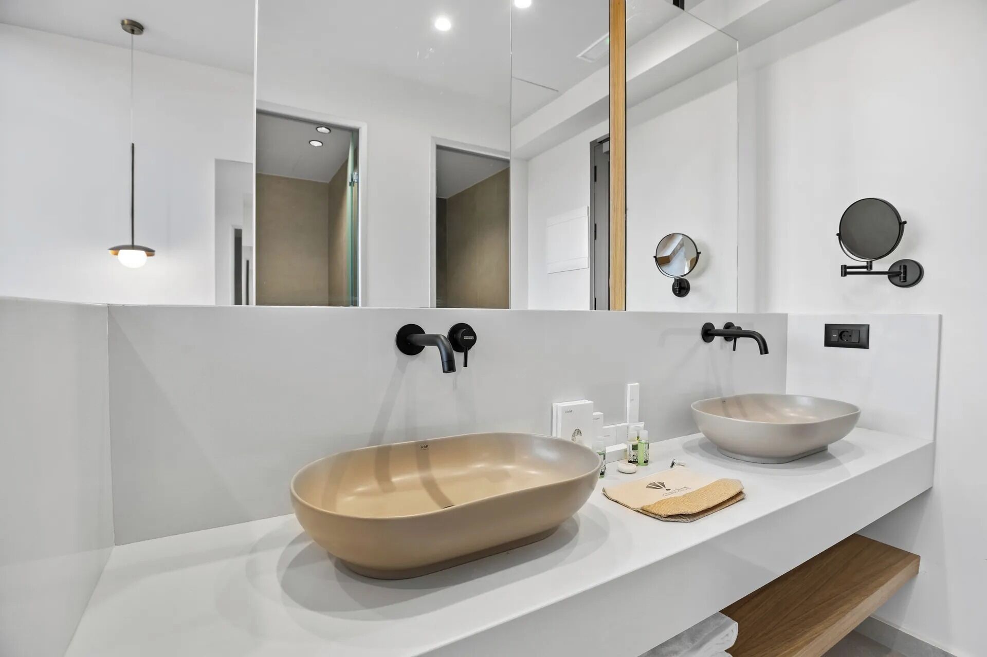 Un baño moderno con dos lavamanos grandes, un espejo y un perchero para toallas.