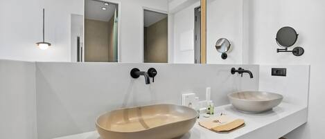 Un baño moderno con dos lavamanos grandes, un espejo y un perchero para toallas.