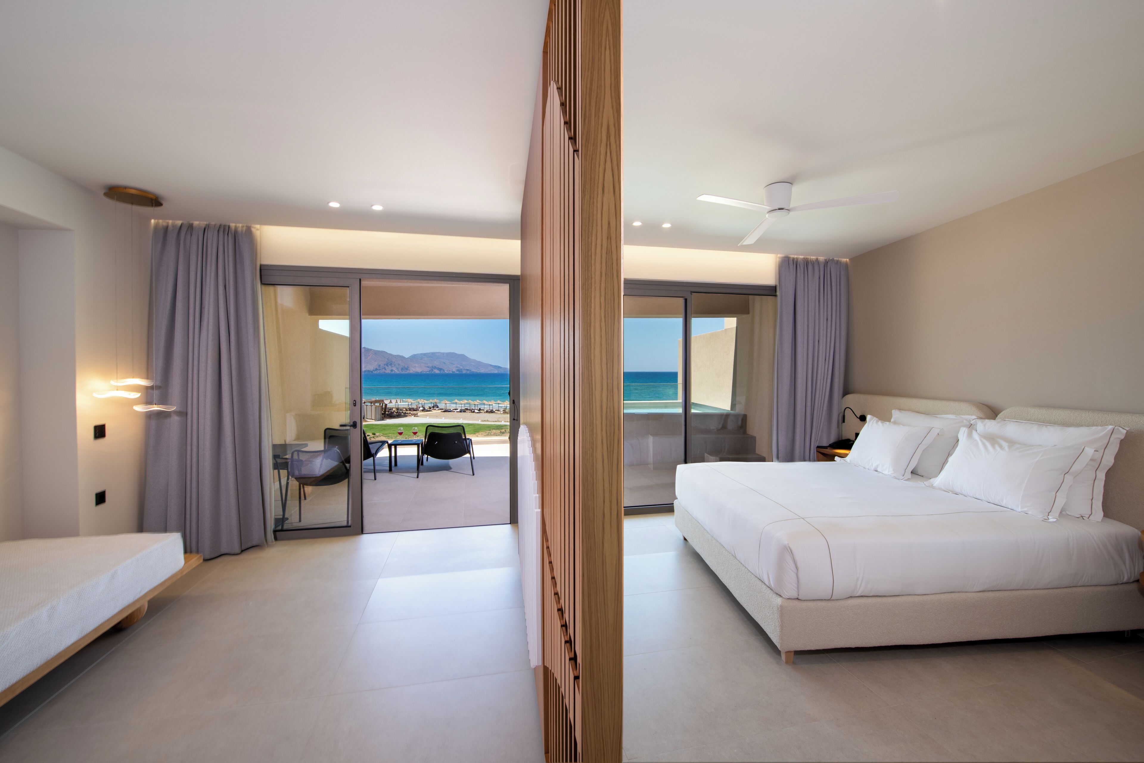 Habitación de hotel moderna con una cama grande, un escritorio y vistas a la playa.