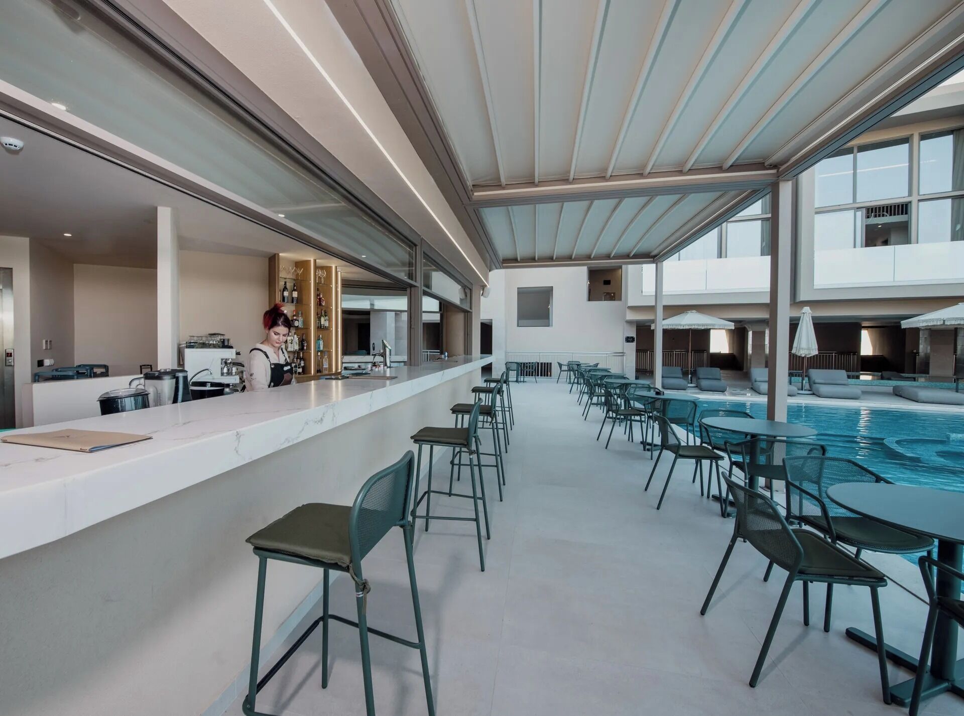 A modern poolside area with a bar, seating, and a view of the pool.