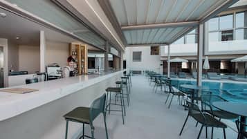 Un espace moderne aménagé au bord de la piscine, avec un bar, des sièges et une vue sur la piscine.