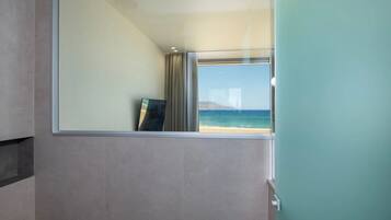 Una habitación con un ventanal que ofrece vistas a la playa y una montaña distante.