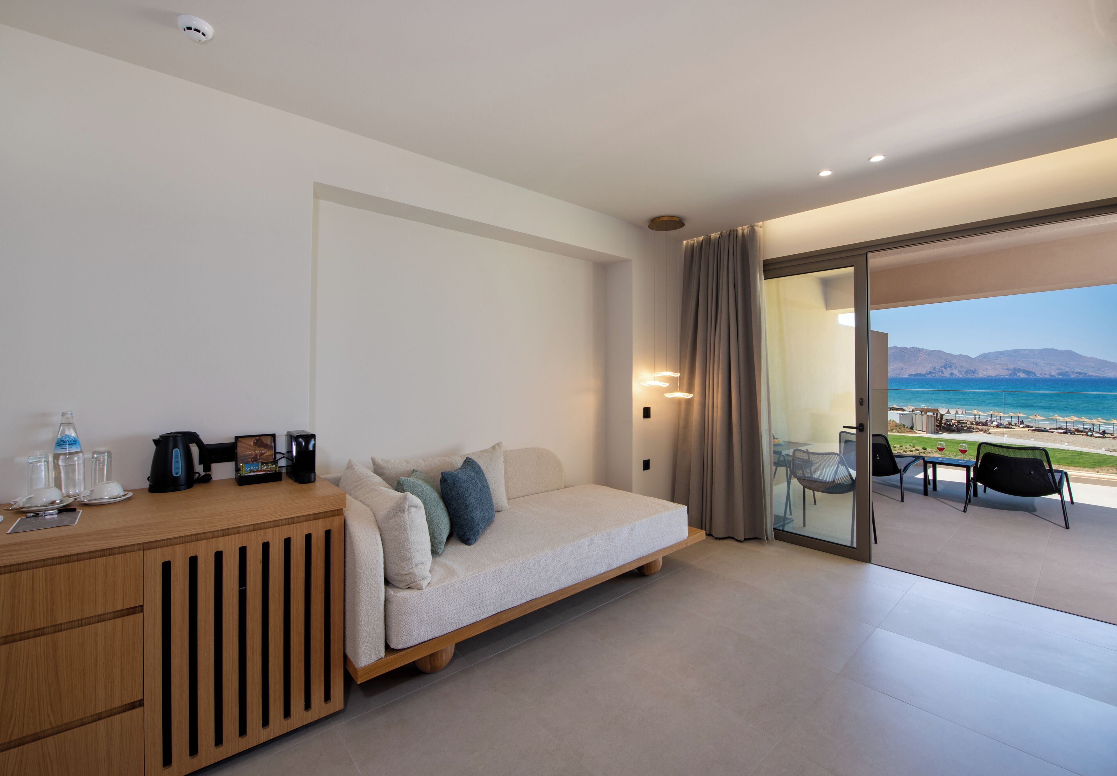 Une chambre d’hôtel moderne équipée d’un canapé-lit, d’une table d’appoint en bois et d’une cloison en verre.
