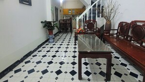 A dining area with a glass table, wooden chairs, and a tiled floor. There is a staircase in the background leading to another room. - Tiny homes  (Hanoi)