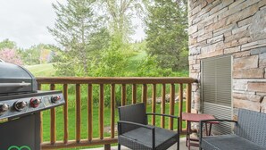 A patio with a grill, wicker chairs, and a table. - 2 BDRM Condo - Superb Facilities - Great Location (Fernie)