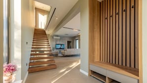 A modern interior with a wooden staircase, a living area with a sofa, and a TV. - Villa Intrada ZadarVillas (Sukošan)