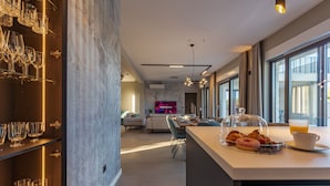A modern kitchen with a breakfast bar, a dining area with a sofa, and a TV in the background. - Villa Intrada ZadarVillas (Sukošan)