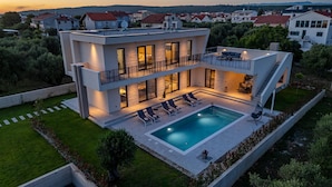 A modern two-story house with a swimming pool, outdoor seating, and a view of the surrounding neighborhood. - Villa Intrada ZadarVillas (Sukošan)