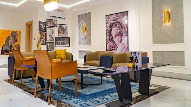 Una sala de estar moderna con un sofá, sillas, una mesa de centro y obras de arte en las paredes.